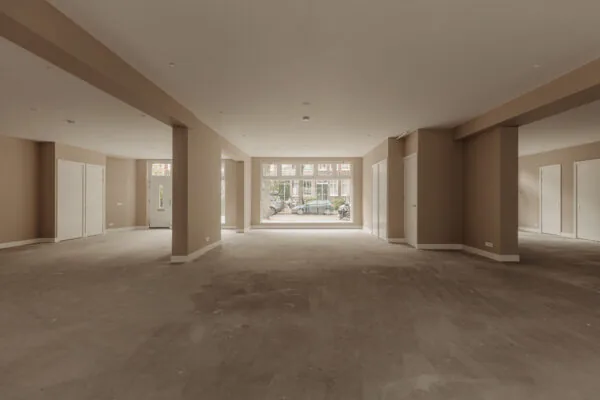 Leegstaand, ruim interieur van een begane grondpand aan de Henri Polaklaan met zicht op de straat via grote ramen.